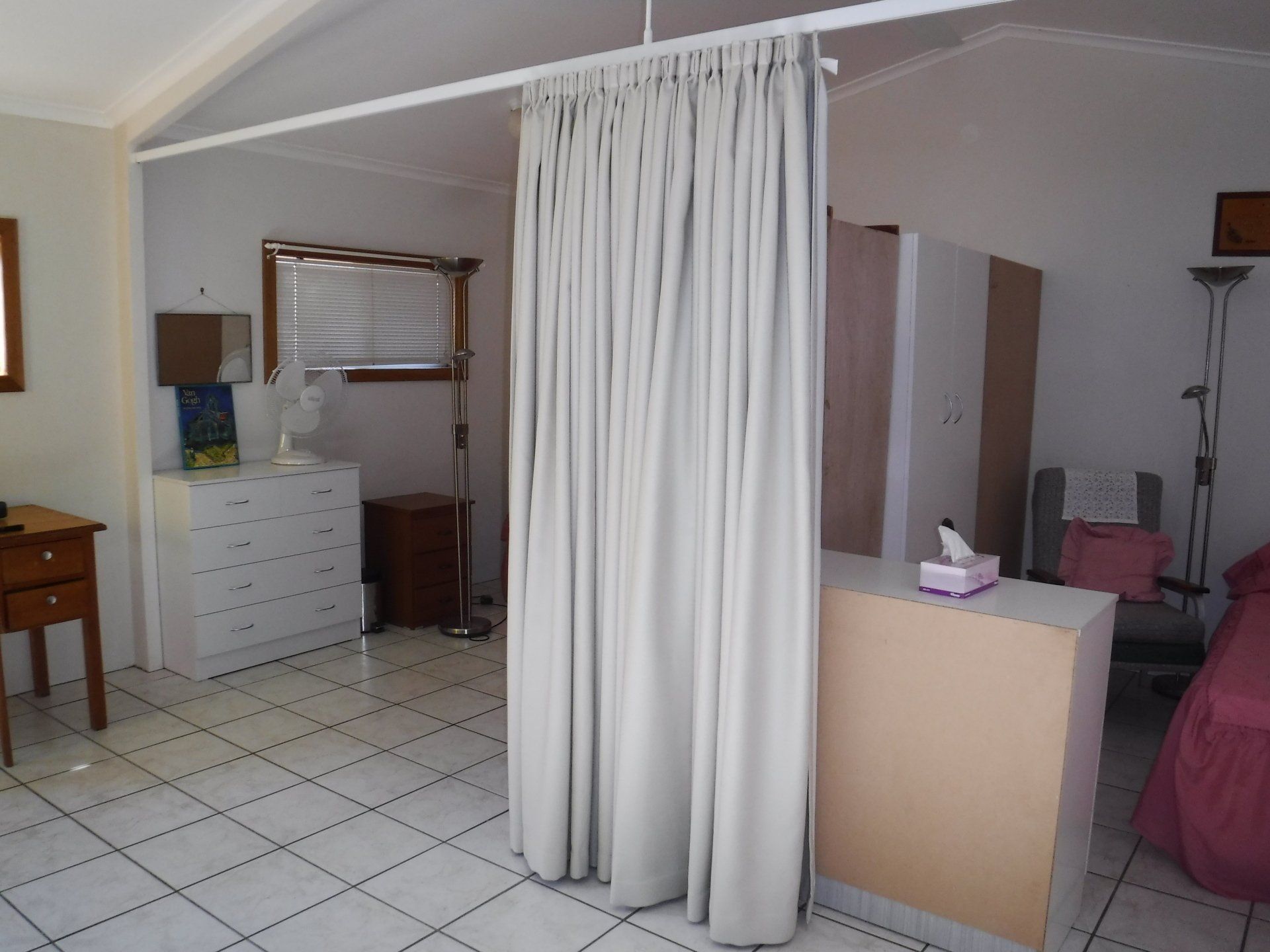 Bedroom with White Tiled Floor Curtains Dividing Space — Alice Mobile Blinds in Ciccone, NT