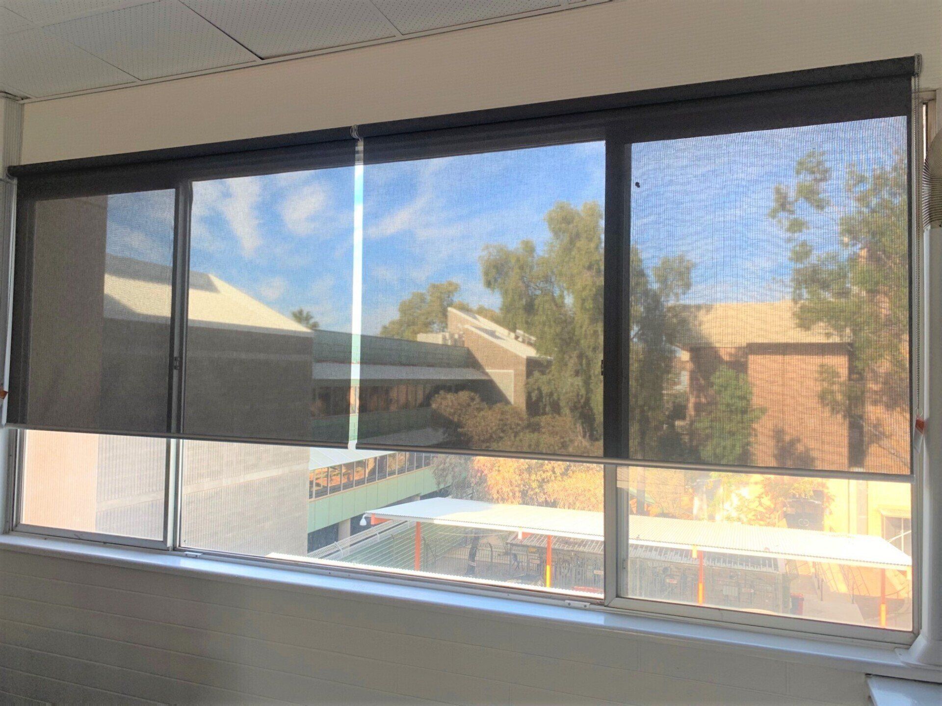 Window with Dark Roller Shades Partially Lowered — Alice Mobile Blinds in Ciccone, NT