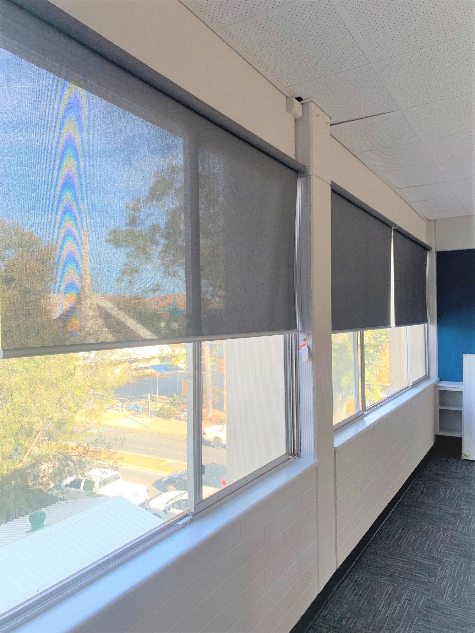 Windows with Grey Roller Shades Partially Covering the Glass — Alice Mobile Blinds in Ciccone, NT