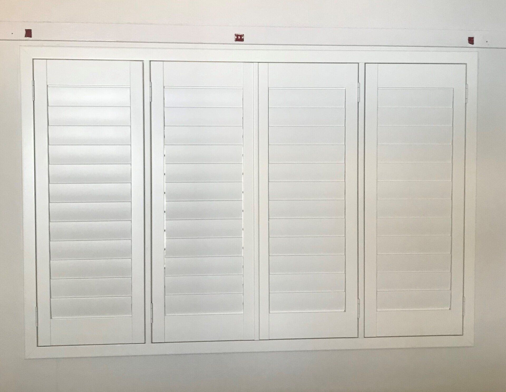 White Shuttered Window, Four Panels, Closed Slats on A White Wall — Alice Mobile Blinds in Ciccone, NT