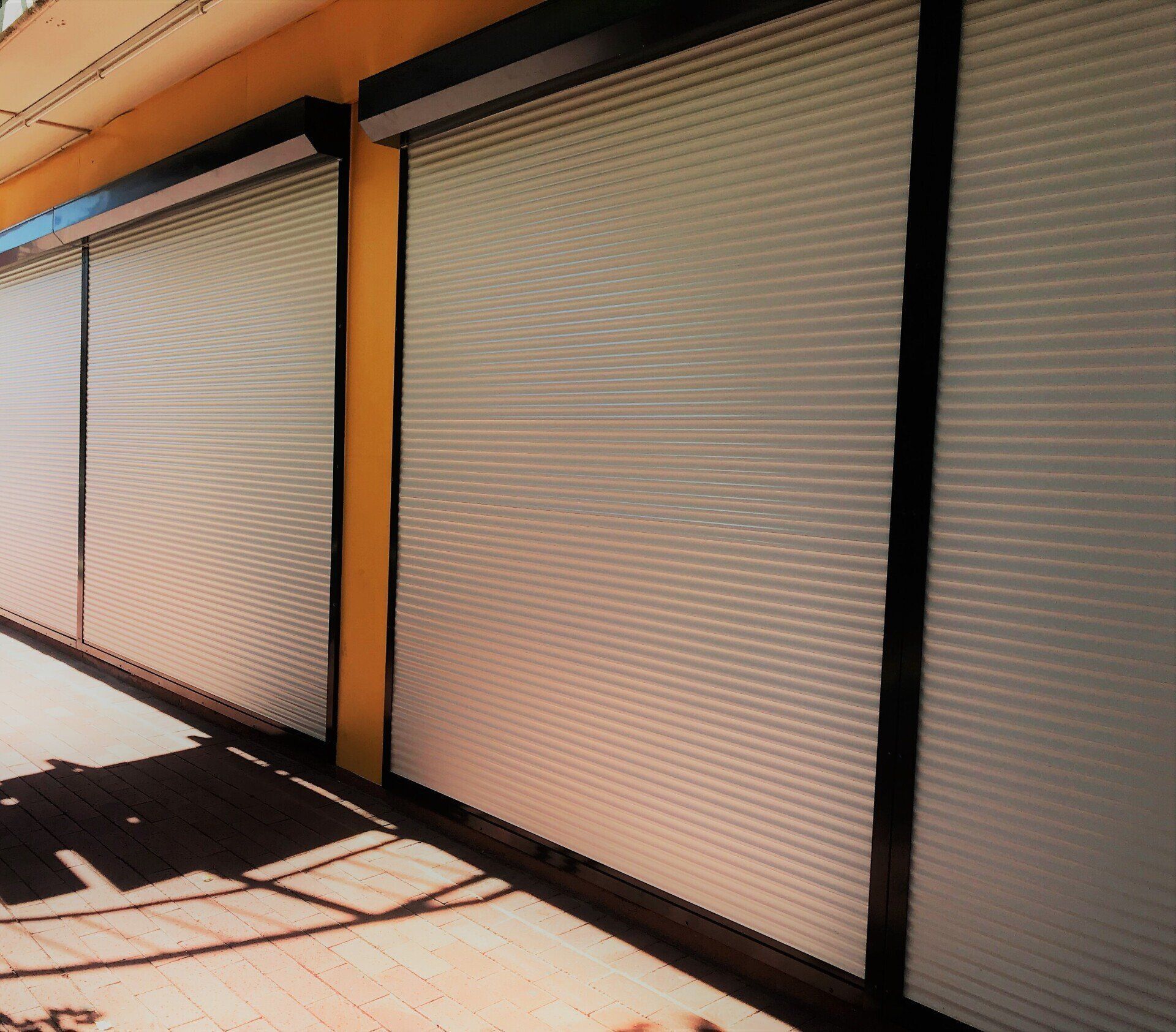 Exterior of Closed Store Fronts with White Roller Shutters — Alice Mobile Blinds in Ciccone, NT