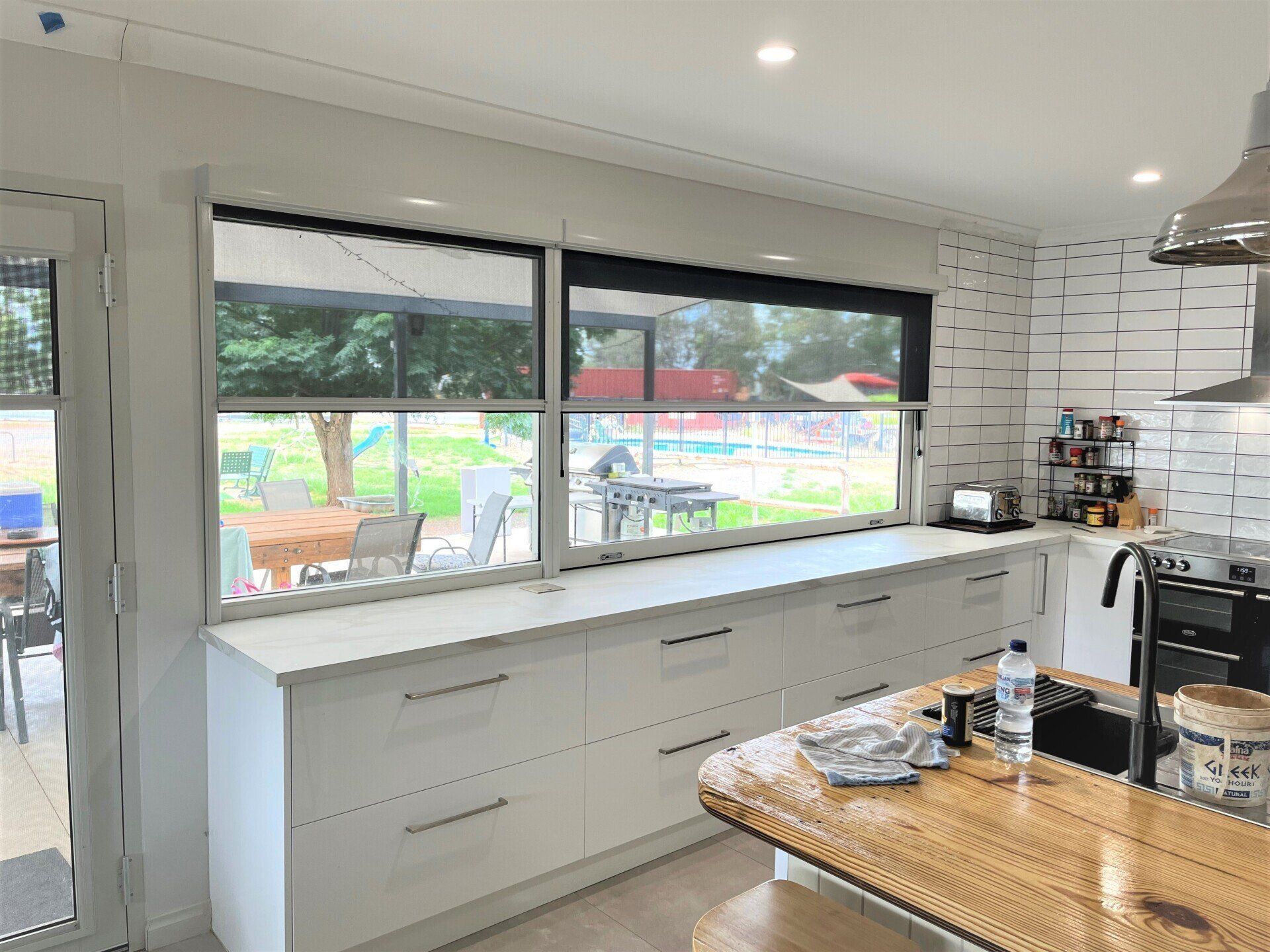 Kitchen with White Cabinets, Dark Blinds and View of Outdoor — Alice Mobile Blinds in Ciccone, NT