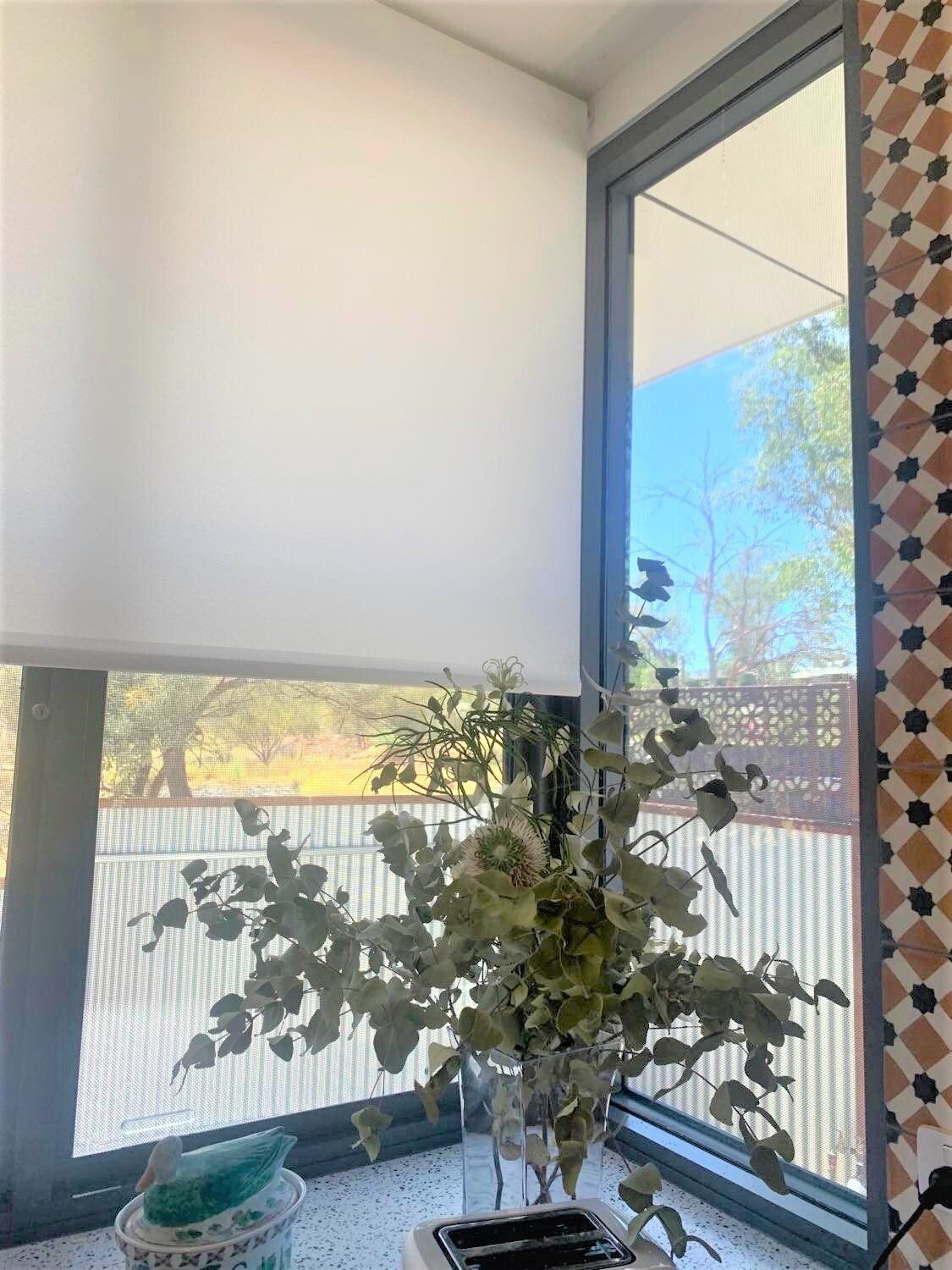 White Window Shade and Floral Arrangement in Front of A Window — Alice Mobile Blinds in Ciccone, NT