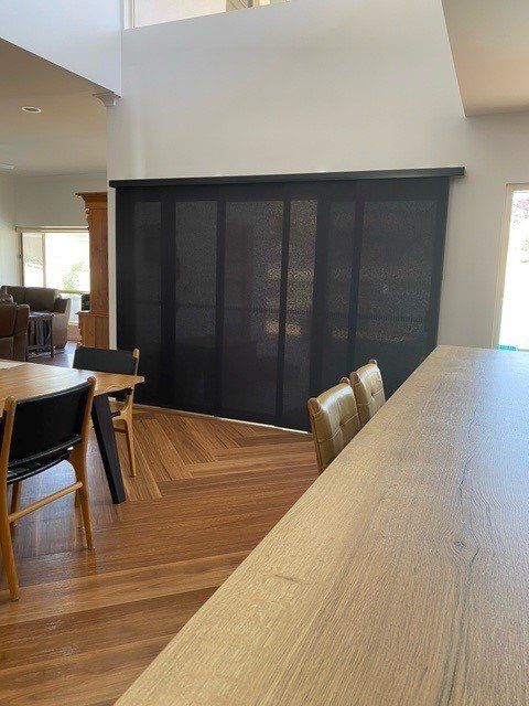 Black Panel Blinds Cover a Window in A Bright Interior with Wood Floors — Alice Mobile Blinds in Ciccone, NT