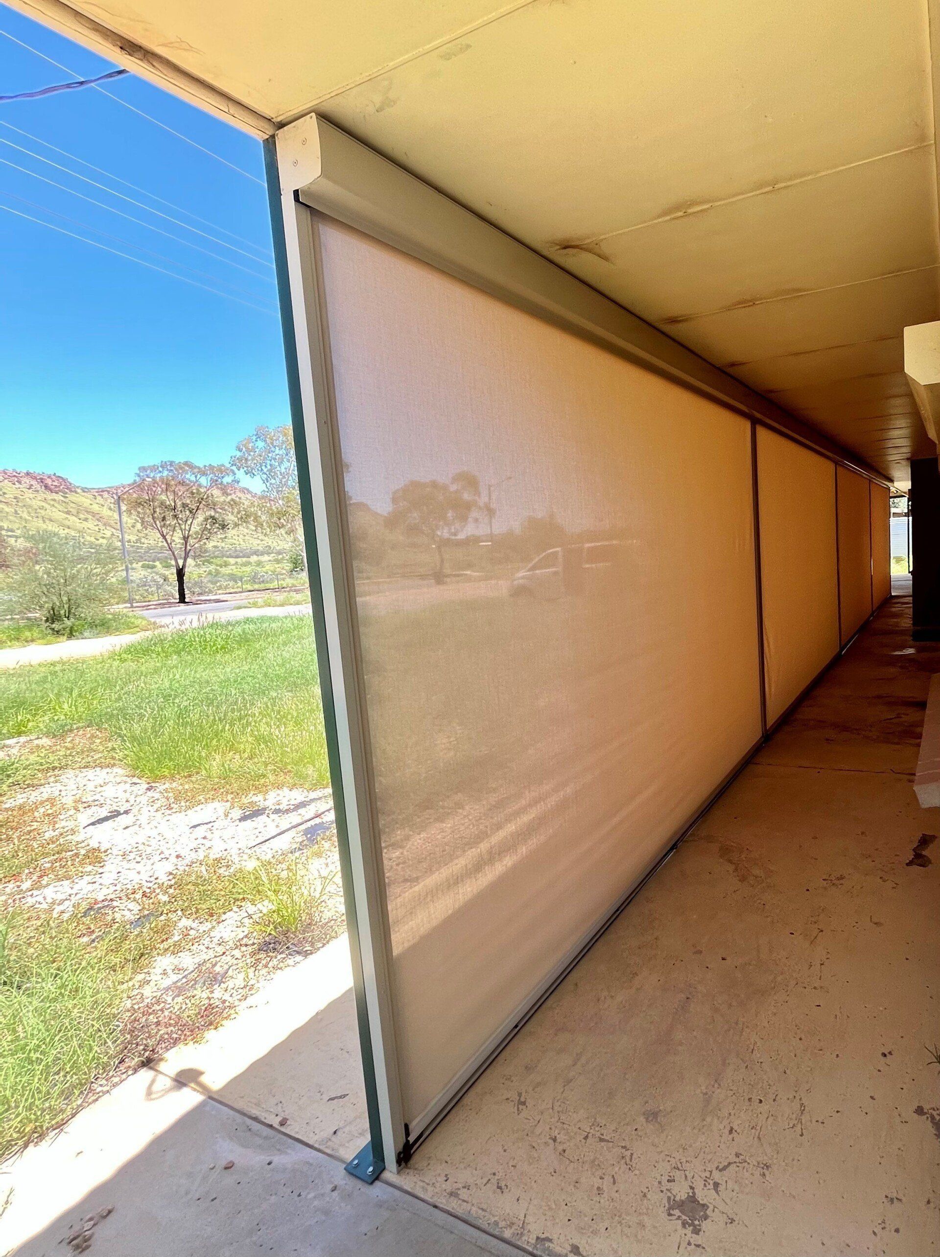 Tan Sunshades Line an Outdoor Walkway — Alice Mobile Blinds in Ciccone, NT