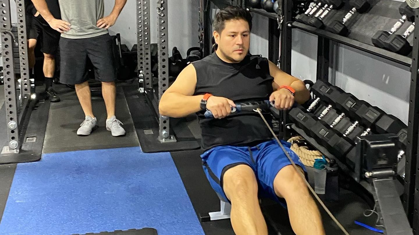 A man is sitting on a rowing machine in a gym.