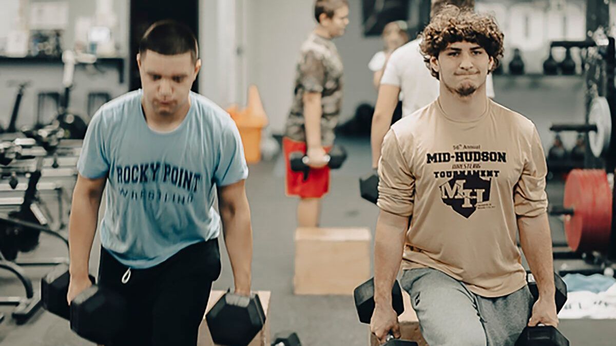 Two men are lifting dumbbells in a gym.