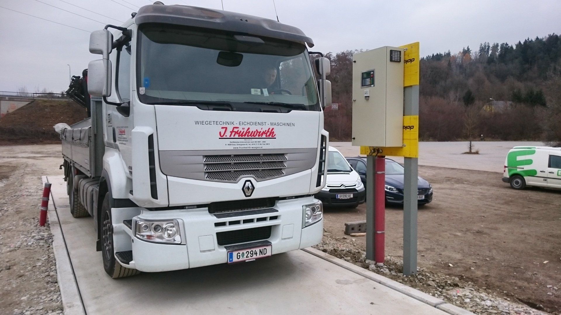 Ein weißer LKW steht auf einer Waage auf einem Parkplatz