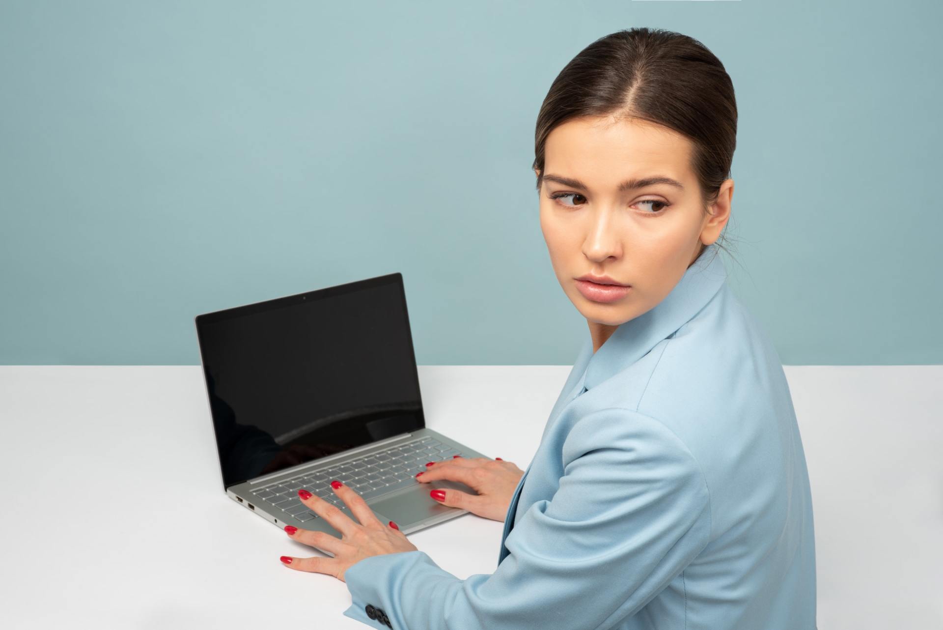 Eine Frau sitzt an einem Schreibtisch und nutzt einen Laptop.