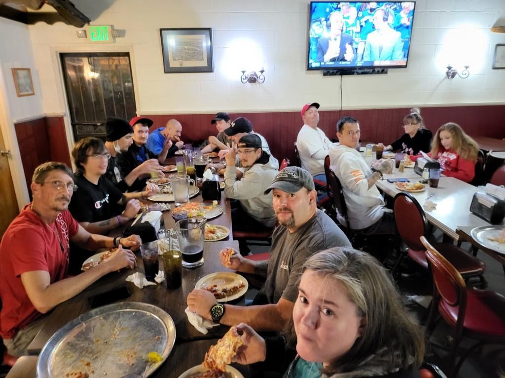 A group of people are sitting at tables in a restaurant eating pizza.