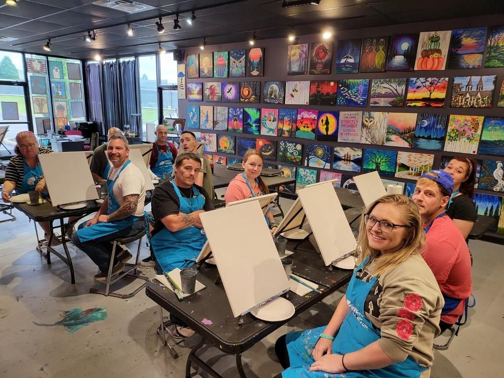 A group of people are sitting at tables in a room with paintings on the wall.