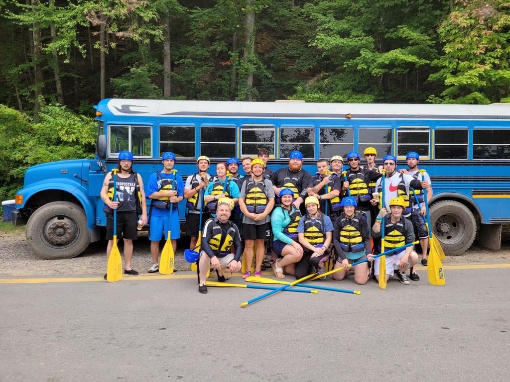 A group of people are posing for a picture in front of a blue bus.