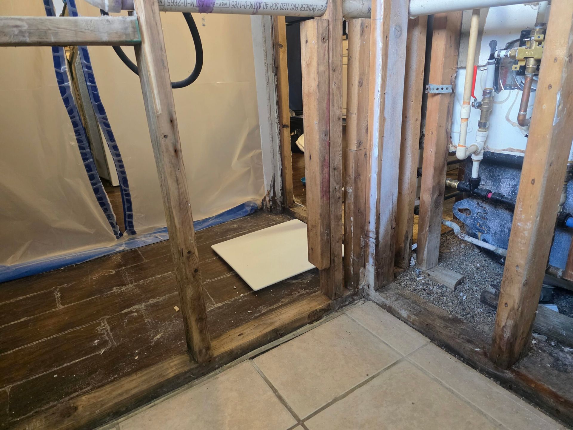 Bathroom renovation in progress, exposed wooden framing, tiles, and plumbing visible.