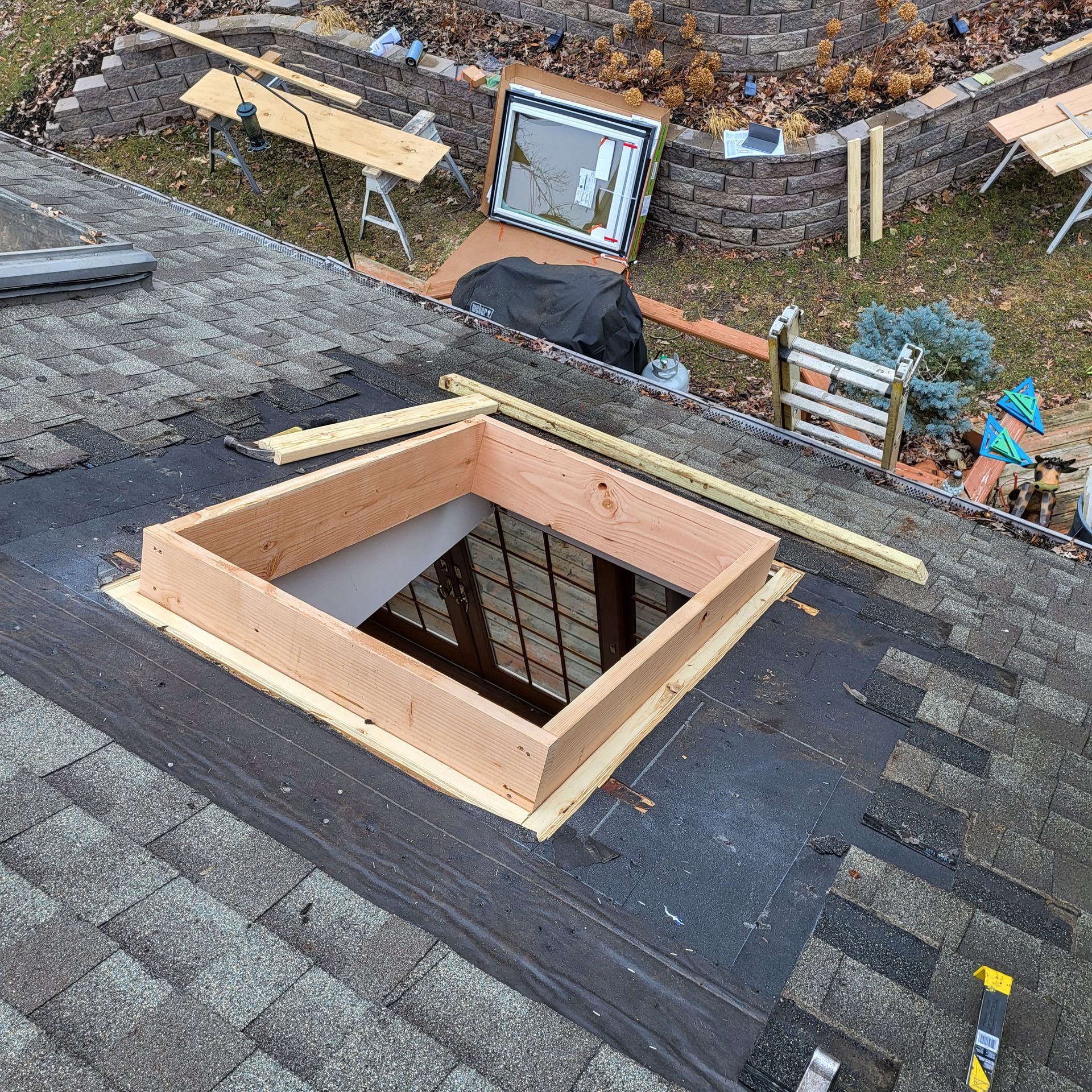 A wooden skylight is being installed on a roof.