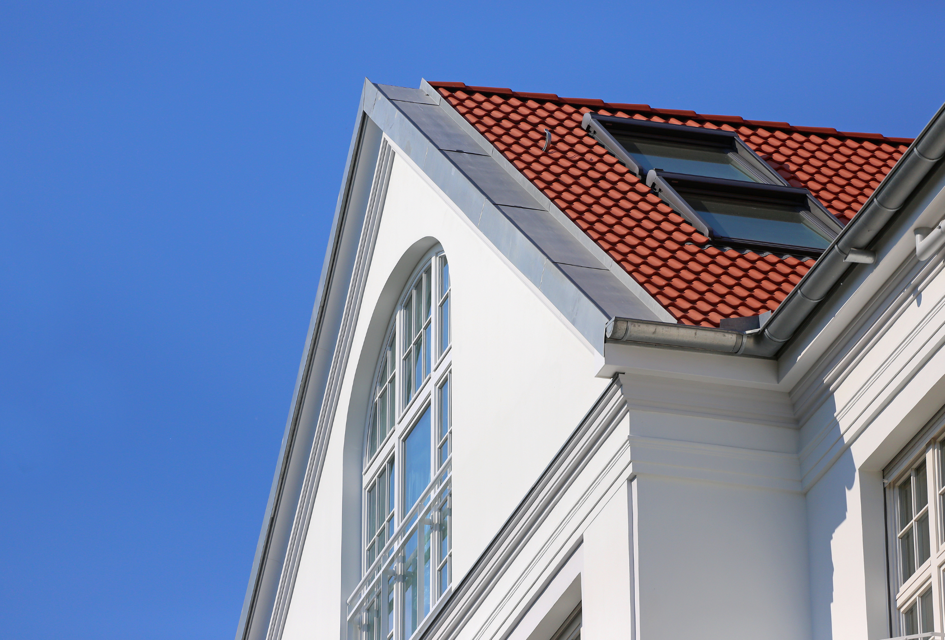 A white building with a red roof and a window