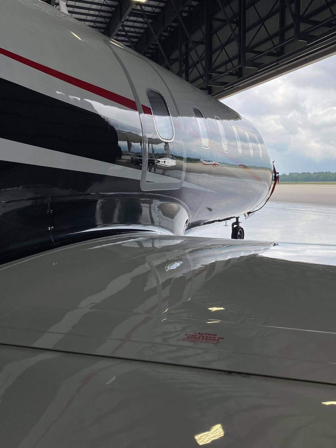 A plane is parked in a hangar with the door open.