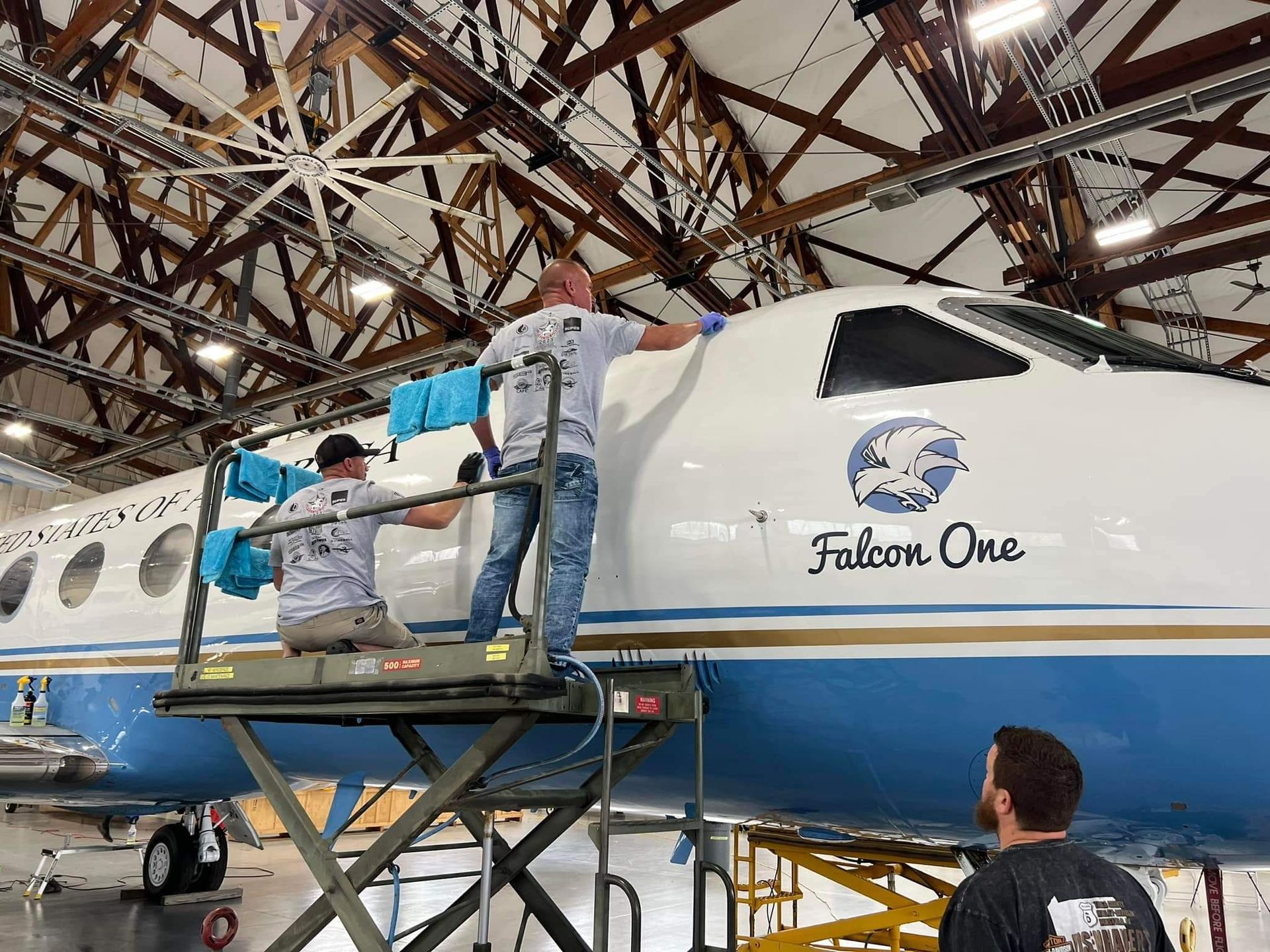 Two men are working on an airplane in a hangar.