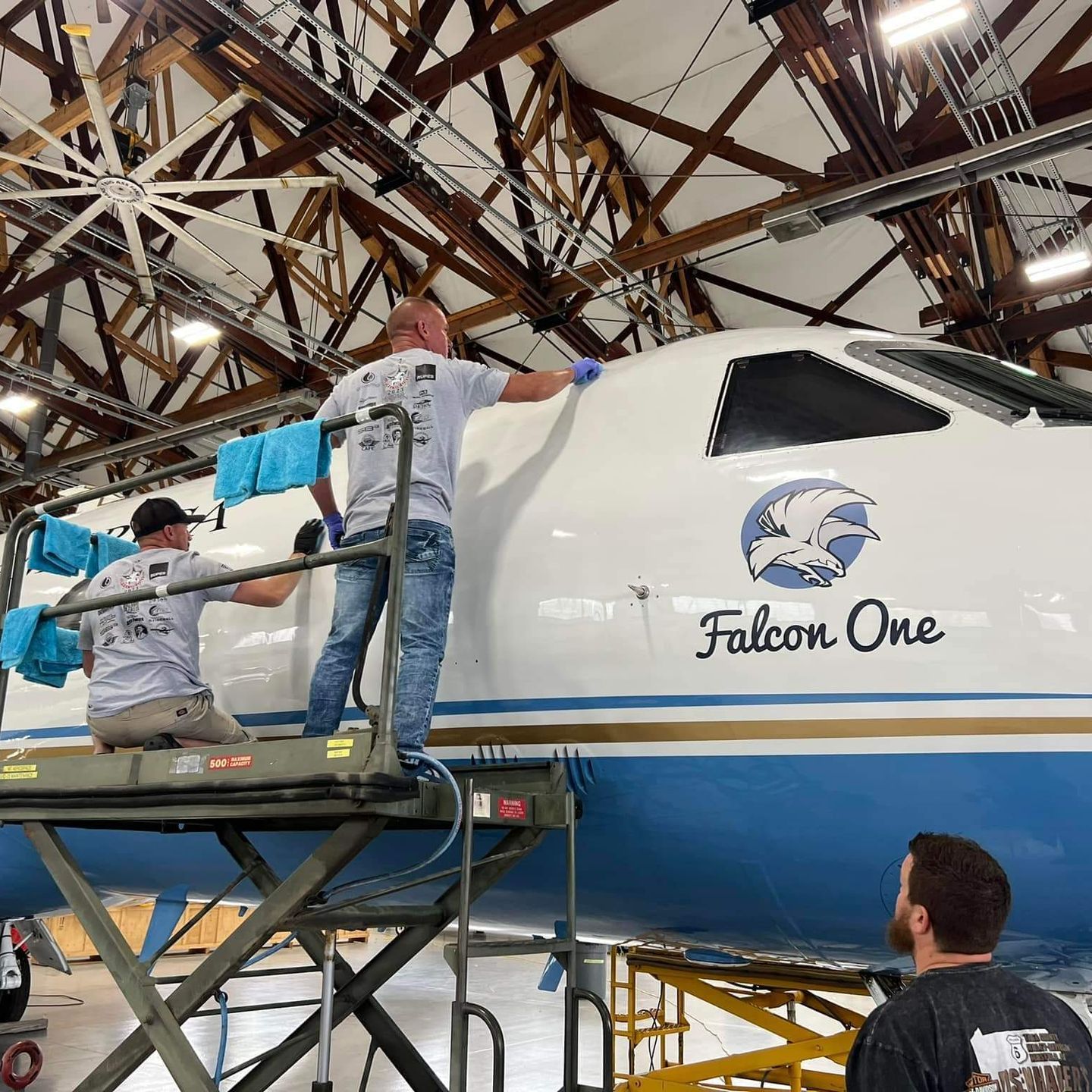 Two men are working on a falcon one airplane in a hangar