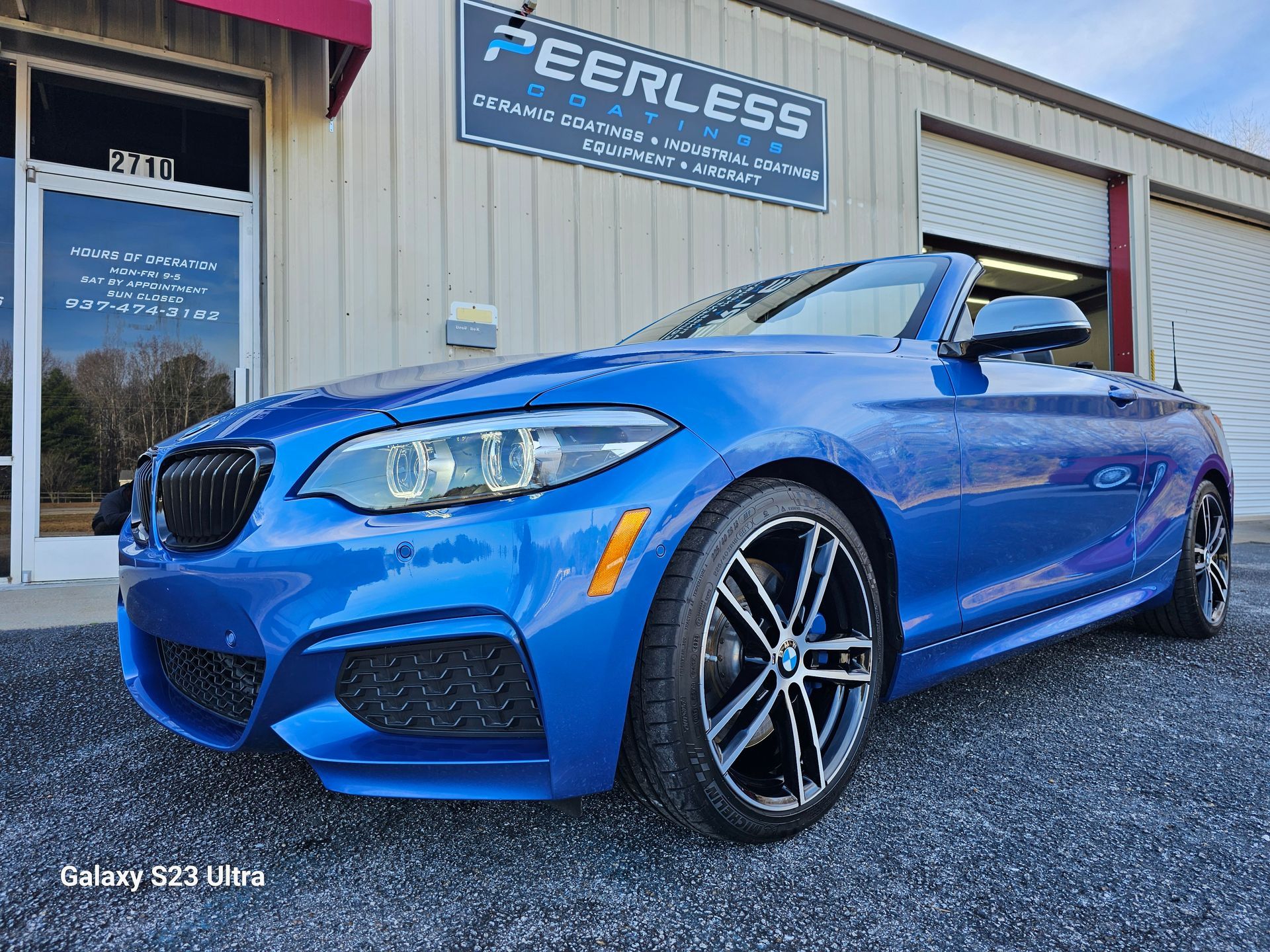 A blue bmw is parked in front of a building.