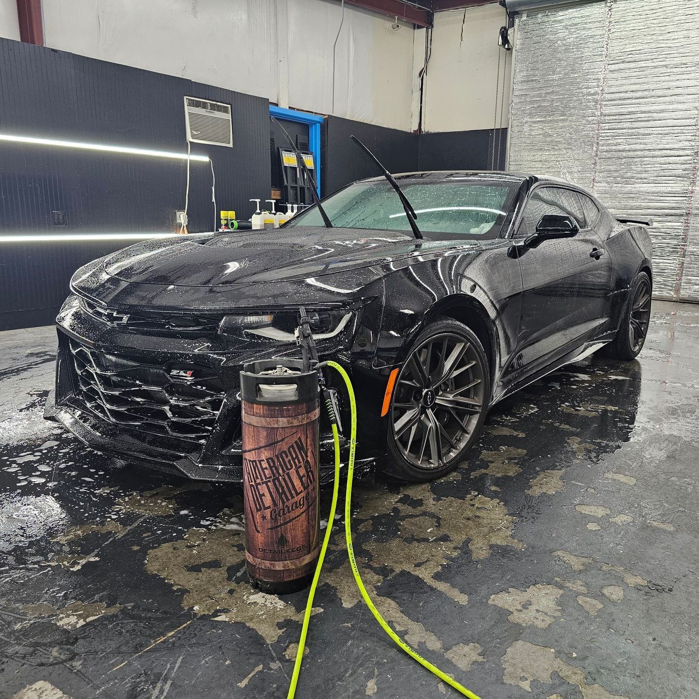 A black car is being washed in a car wash.