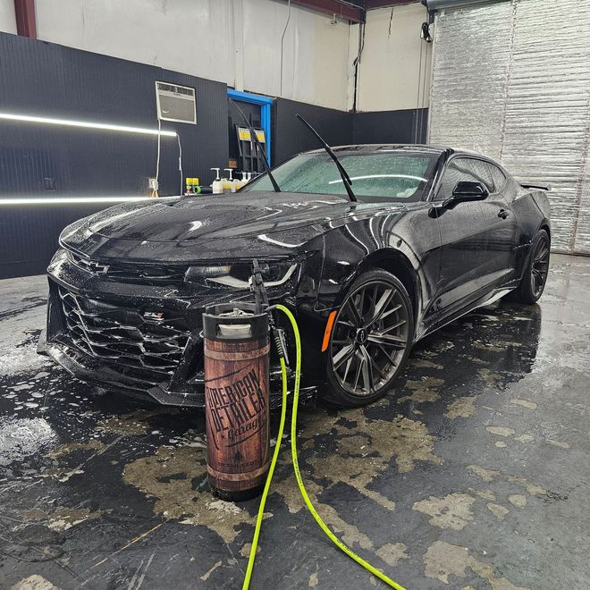 A black car is being washed in a car wash.