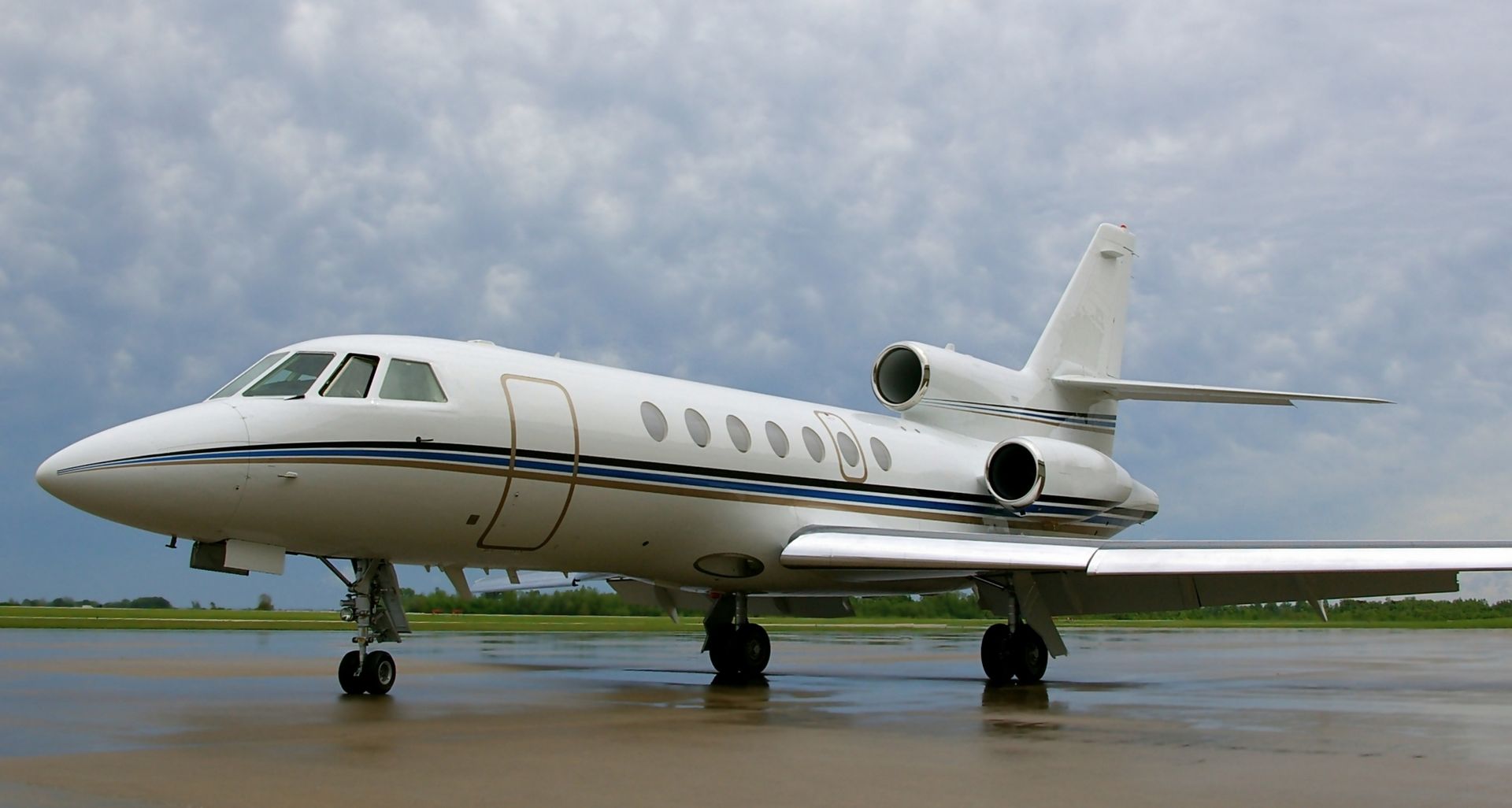 A small white airplane is parked on a wet runway