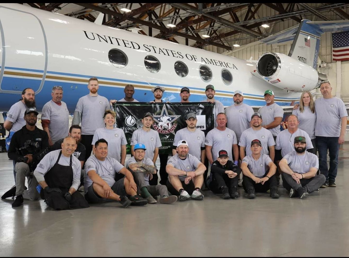 A group of people are posing for a picture in front of a plane that says united states of america