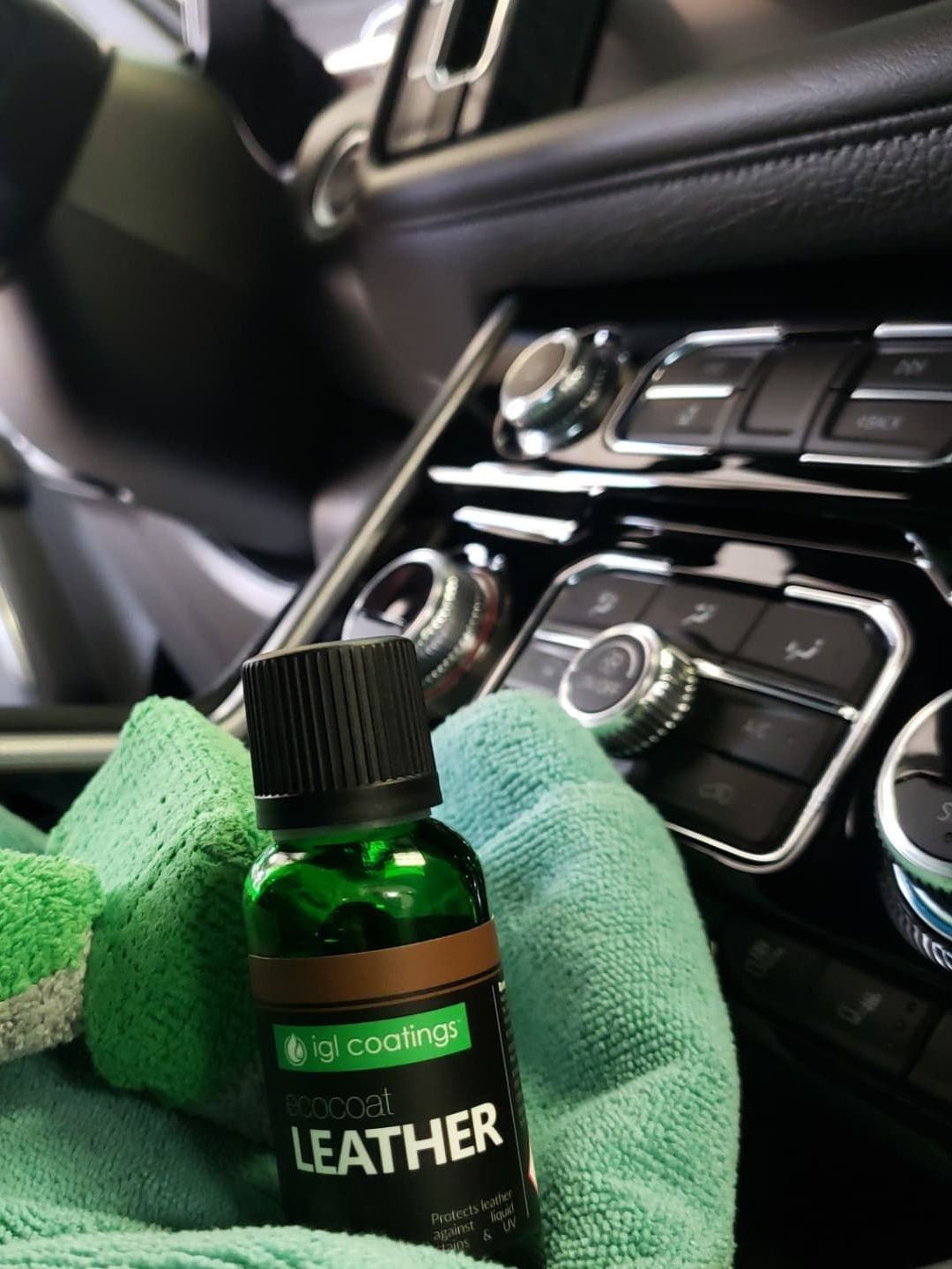 A bottle of leather sitting on top of a green towel in a car.