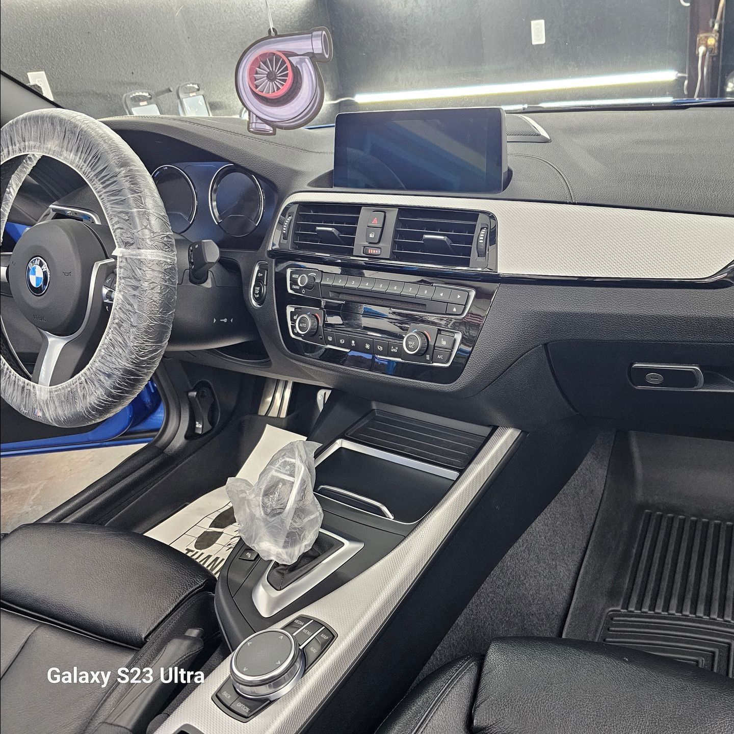 The interior of a bmw with a galaxy s23 ultra.