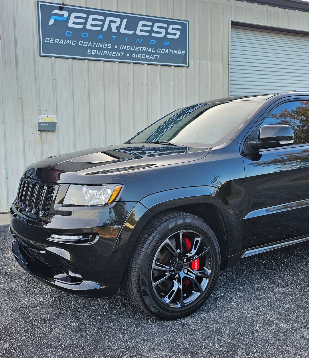 A black jeep grand cherokee is parked in front of a building.