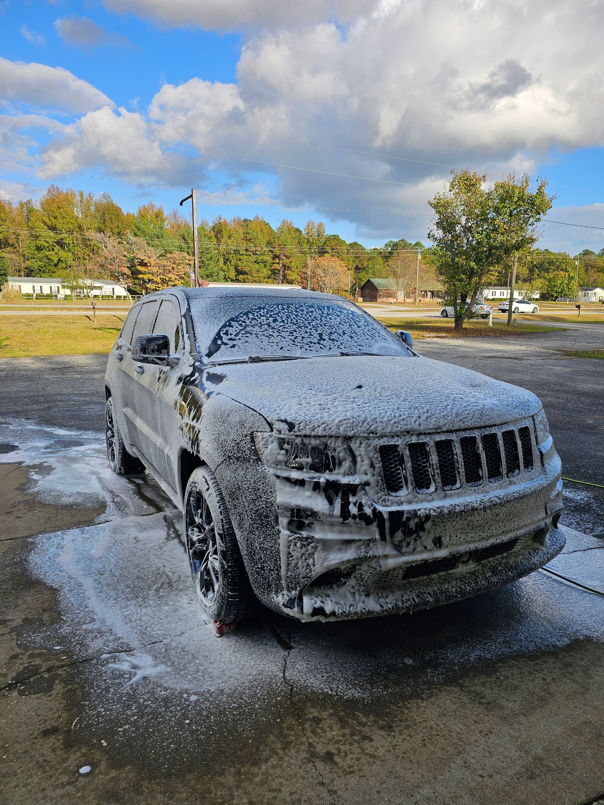 A jeep is covered in foam in a parking lot.