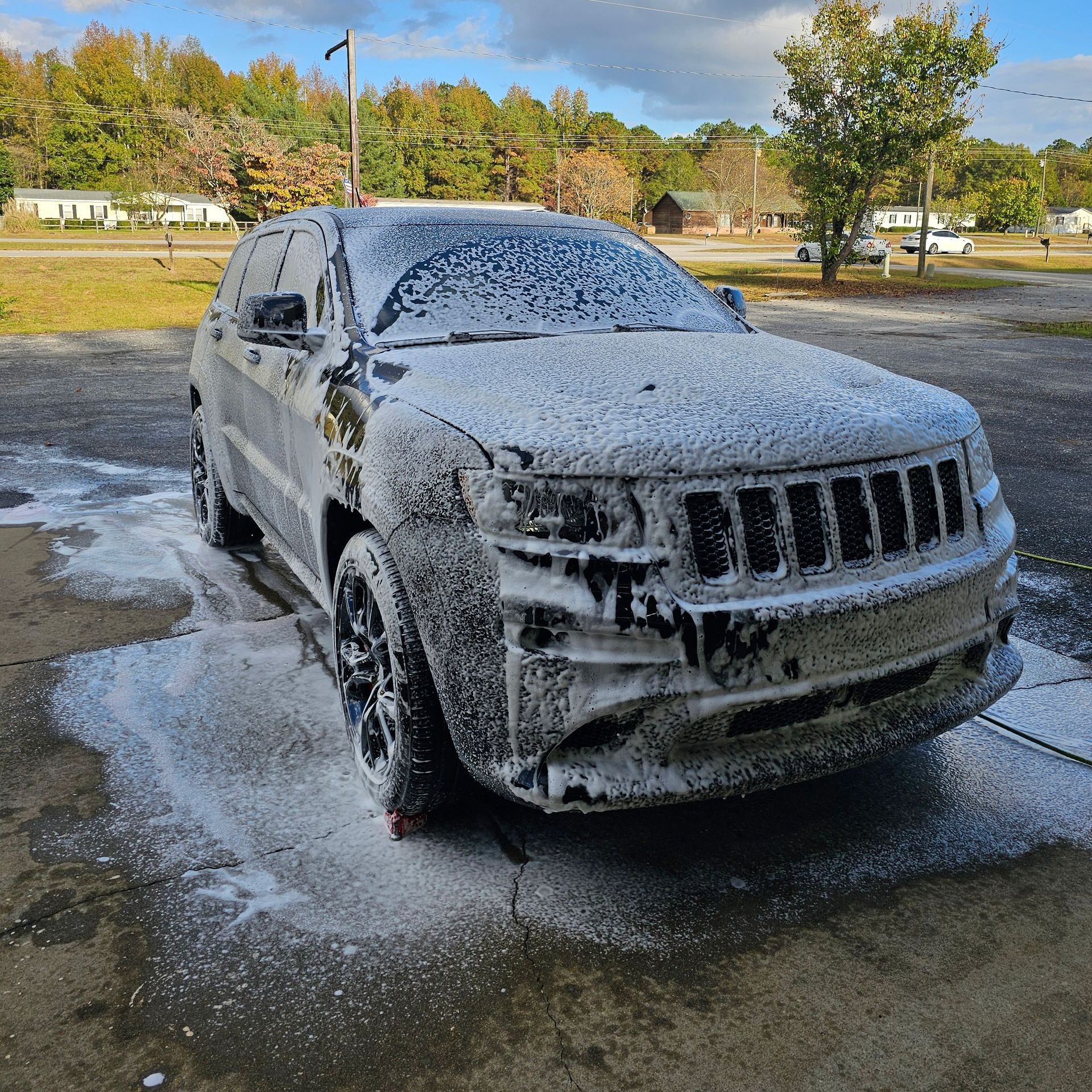 A jeep is covered in foam in a parking lot.