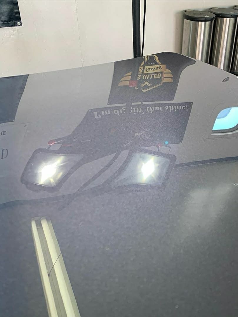 The hood of a car is sitting on a table in a garage.