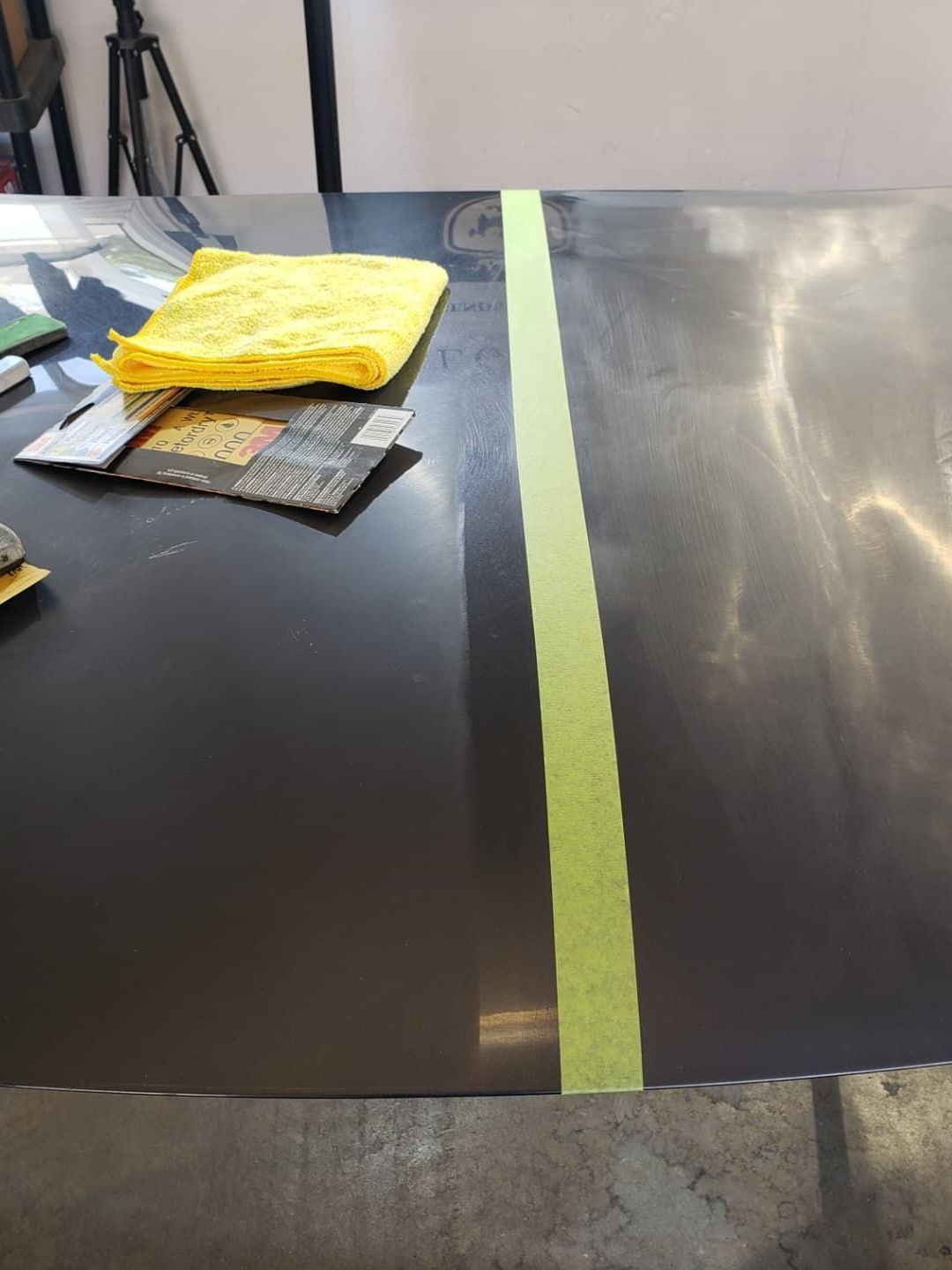 A yellow towel sits on a table next to a green tape line