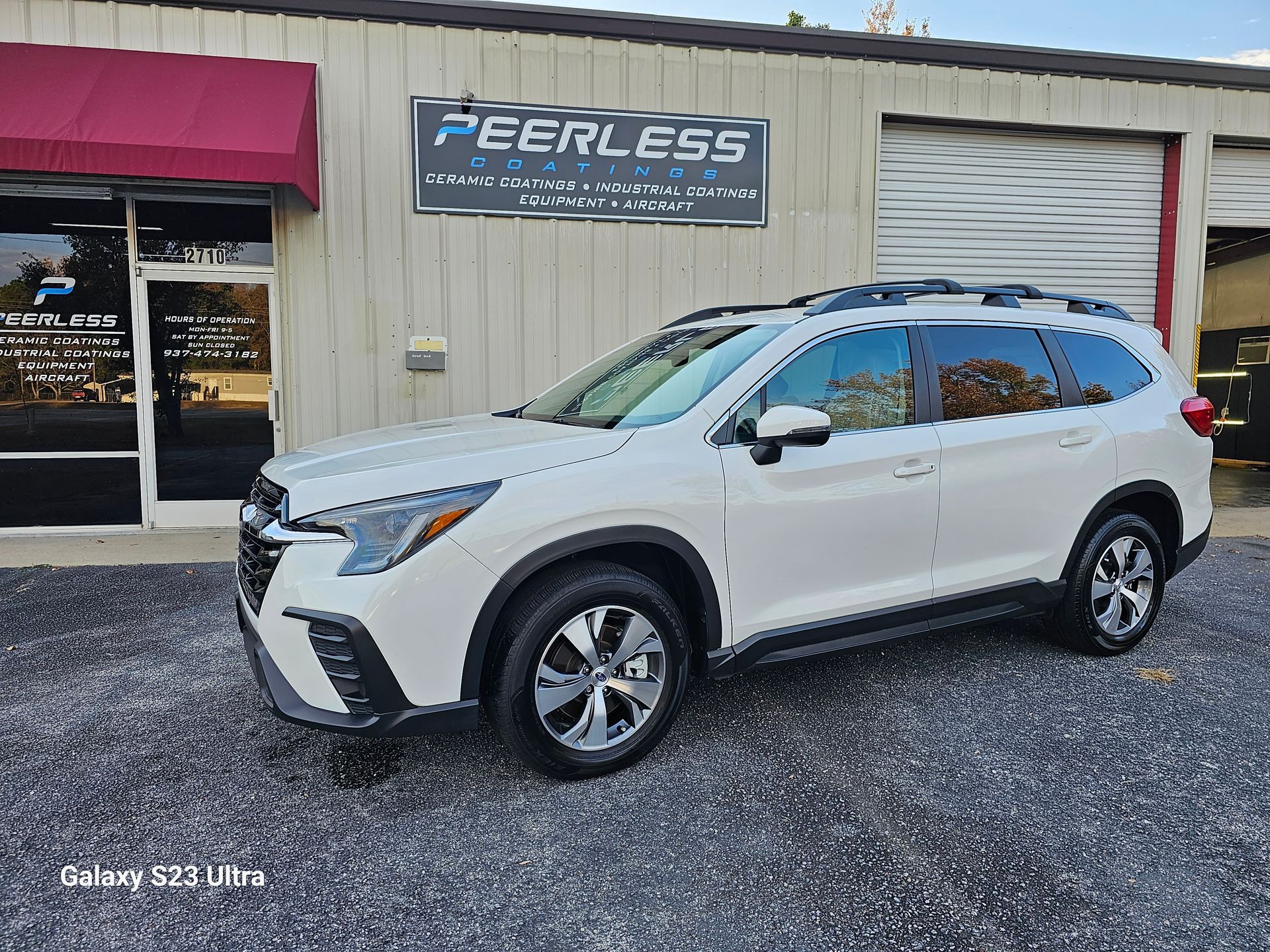 A white suv is parked in front of a building.
