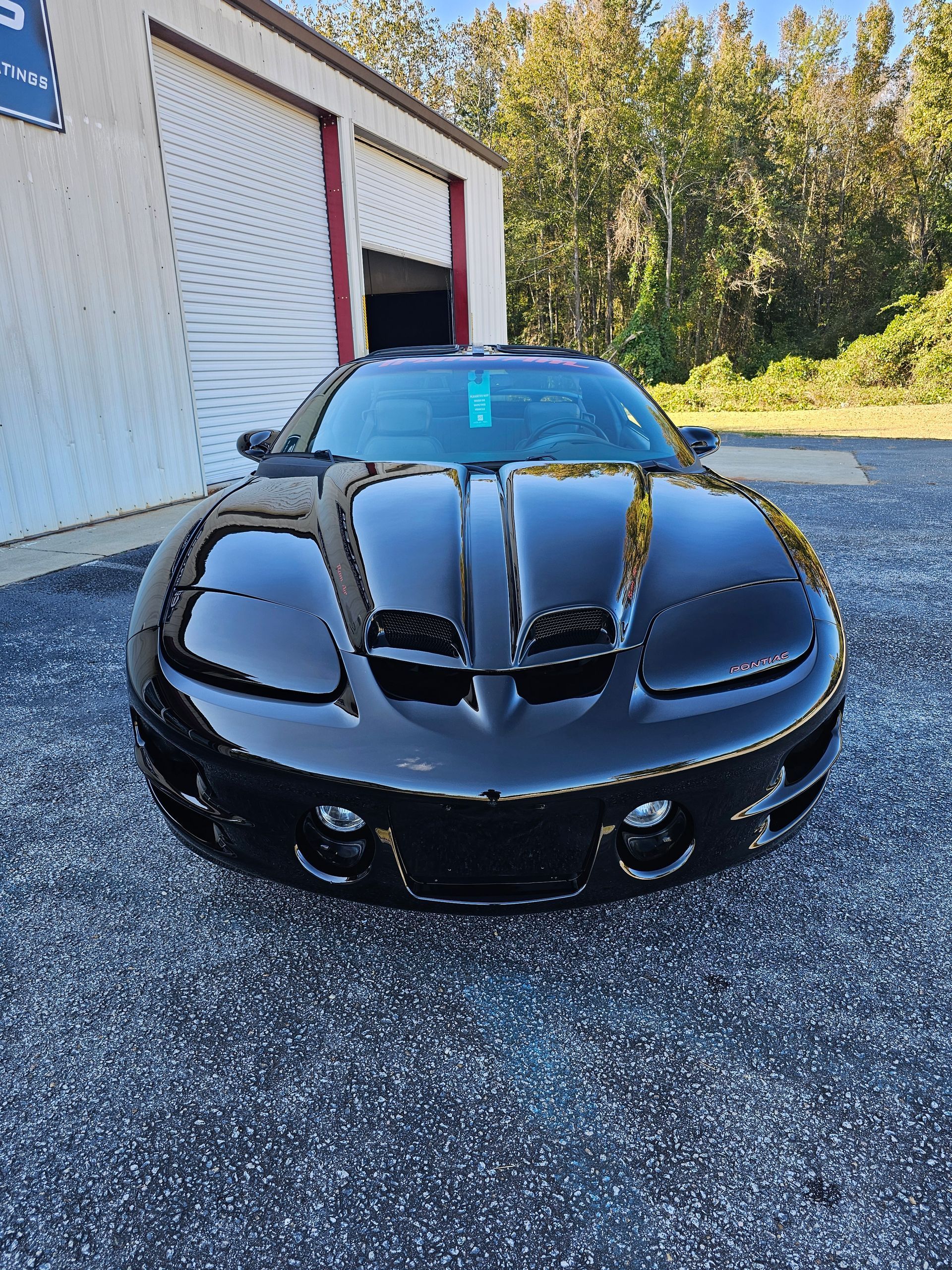 A black sports car is parked in front of a garage.