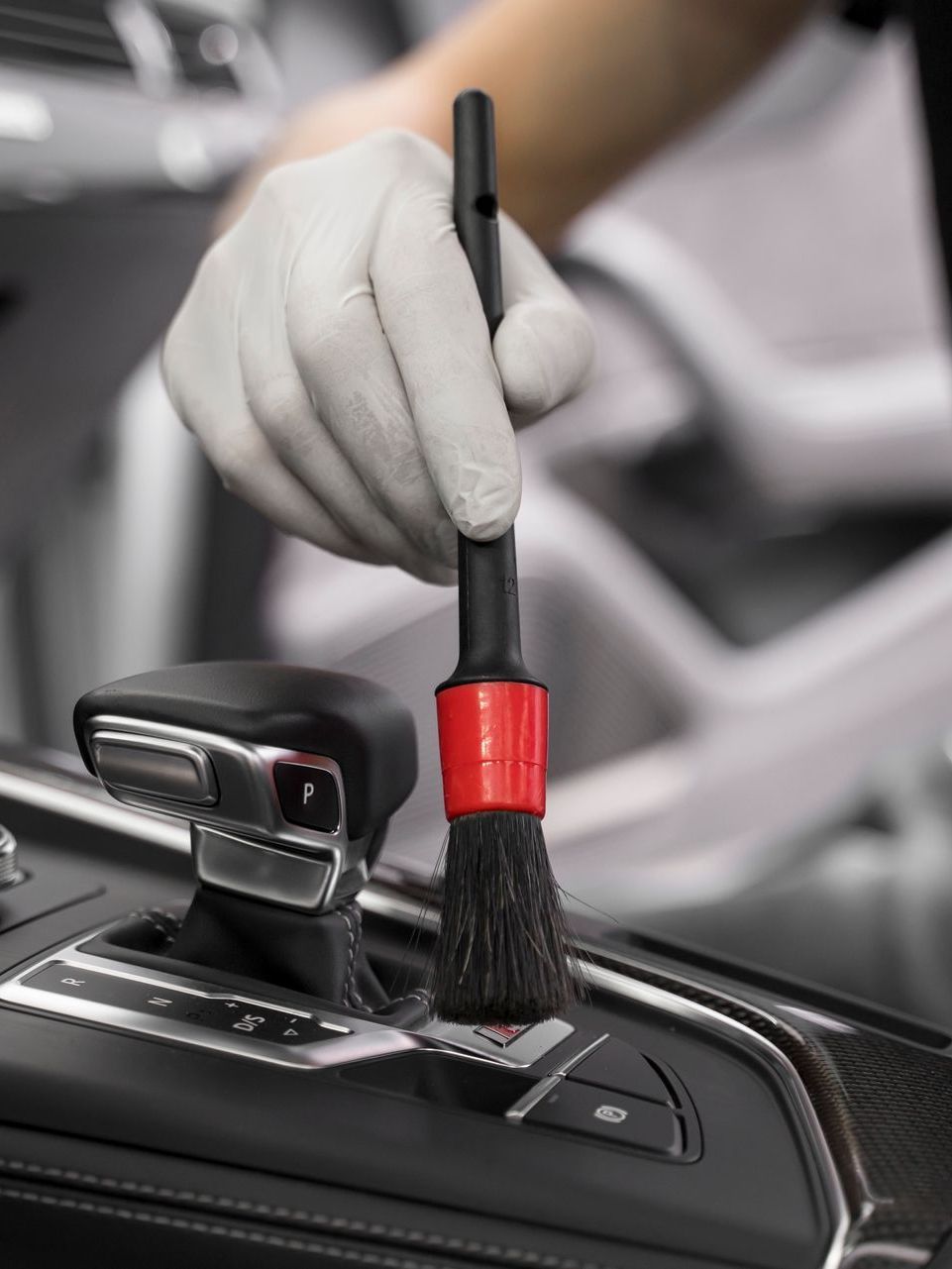 A person is cleaning a car with a brush.