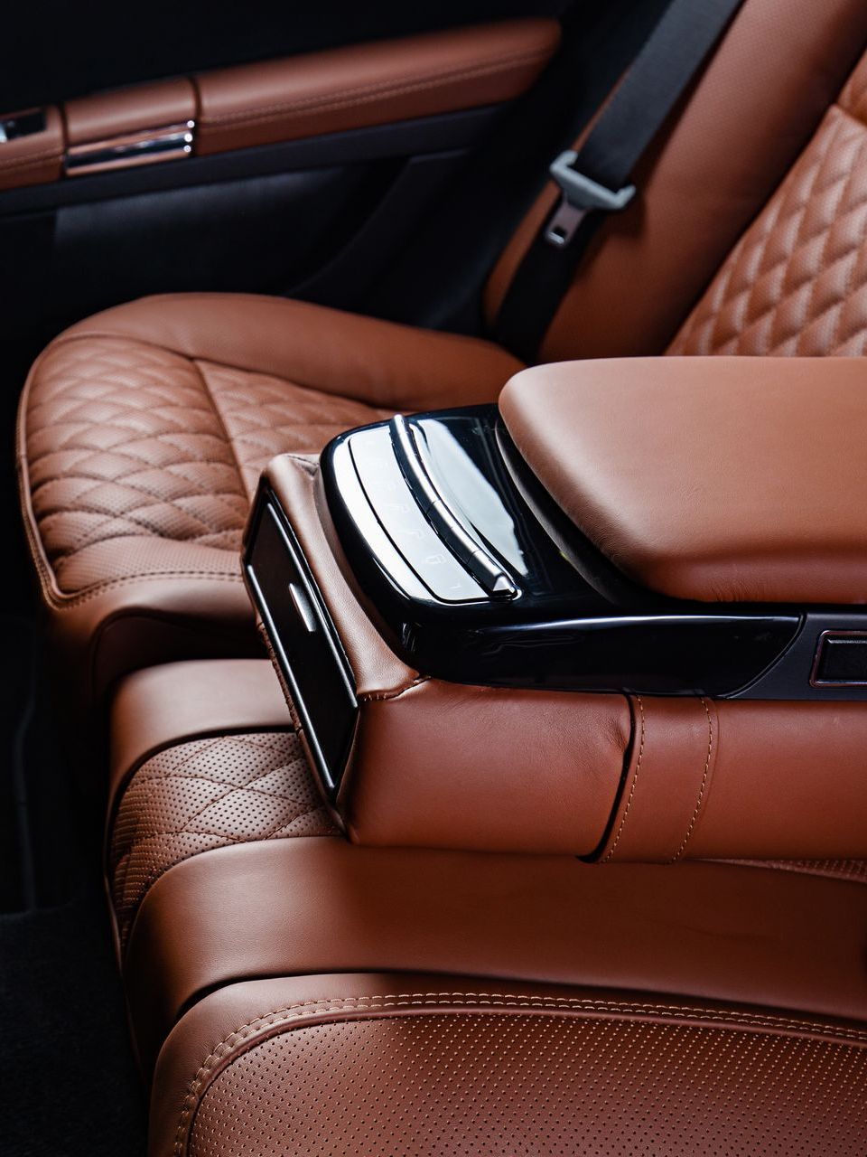 A brown leather car seat with a black arm rest