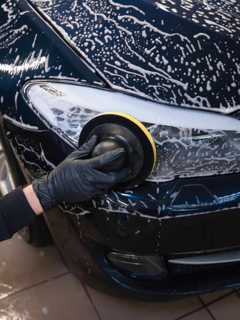 A person is polishing the headlight of a car.