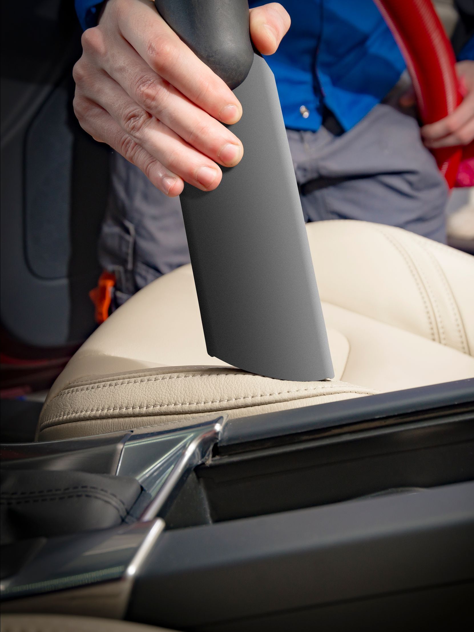 A person is using a vacuum cleaner to clean a car seat
