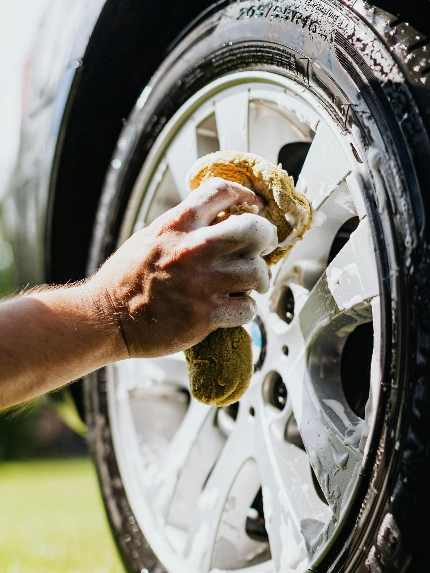 A person is washing a car wheel with a sponge.