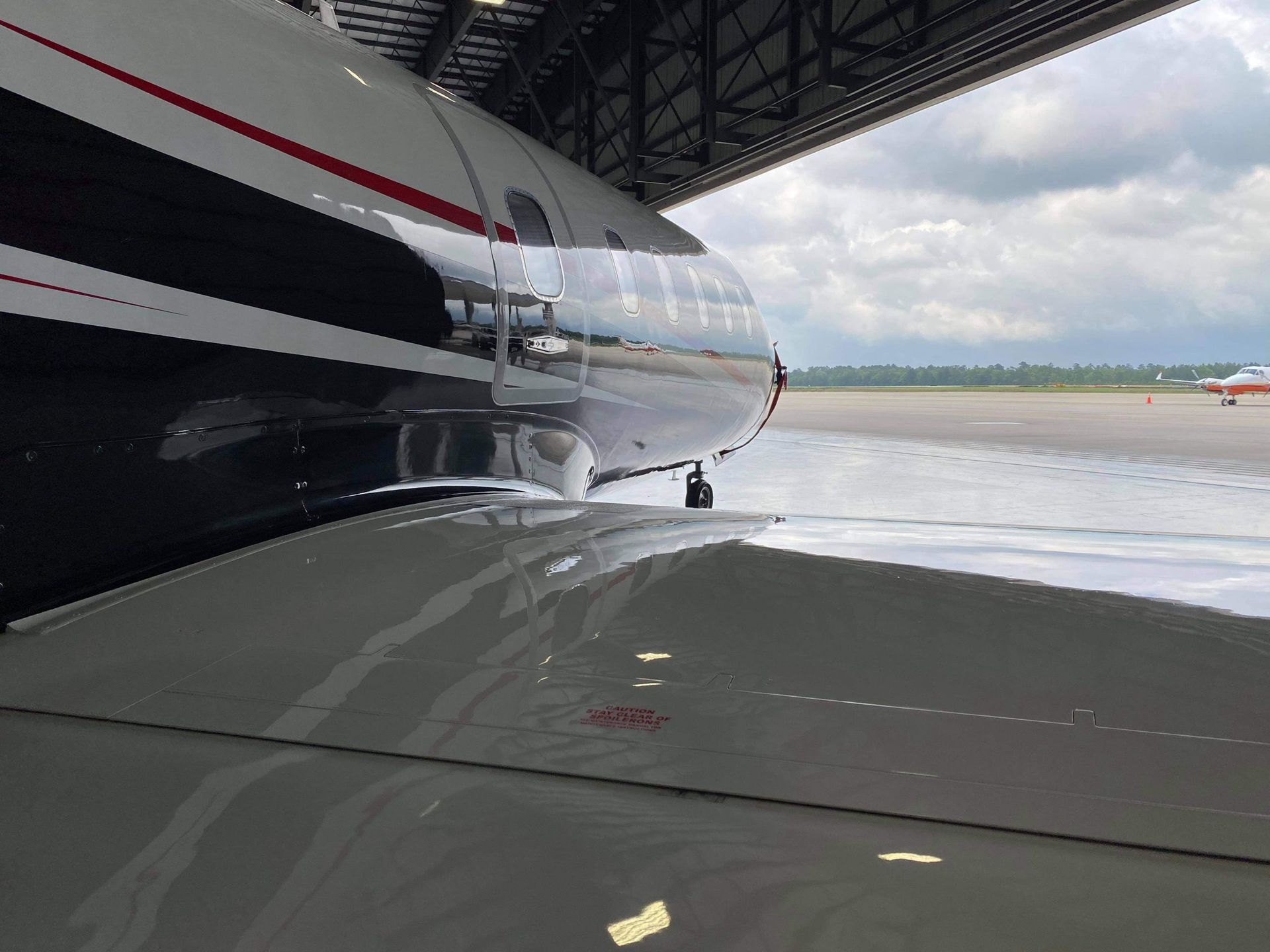 A plane is parked in a hangar with the door open