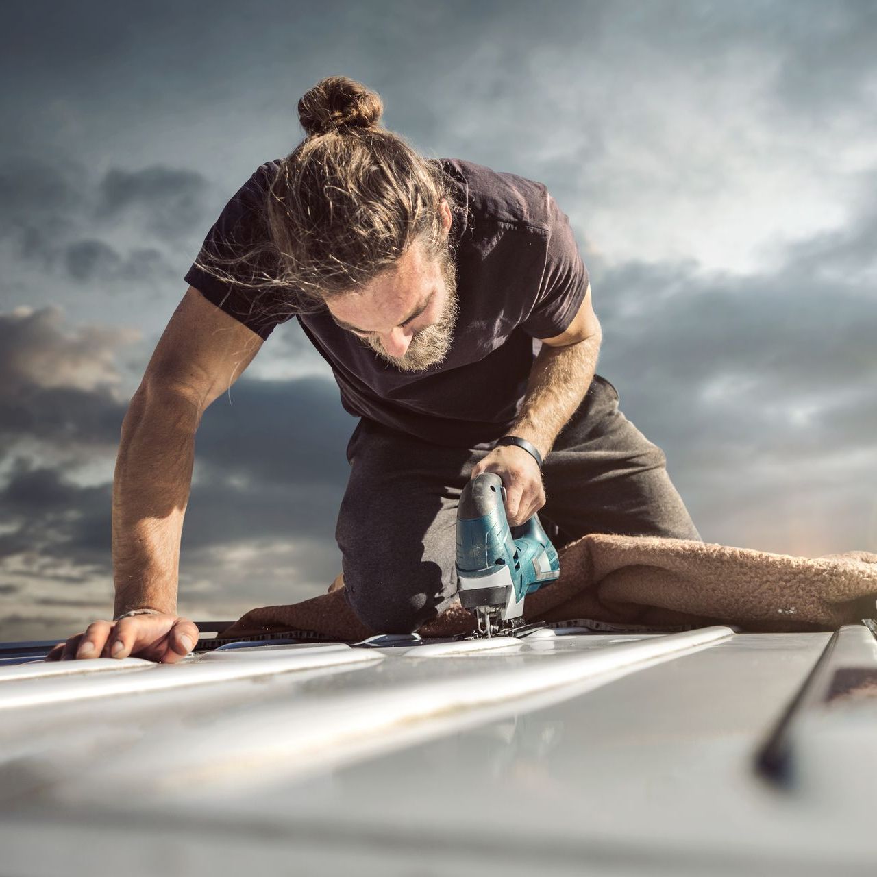 A man is using a jigsaw to cut a piece of wood