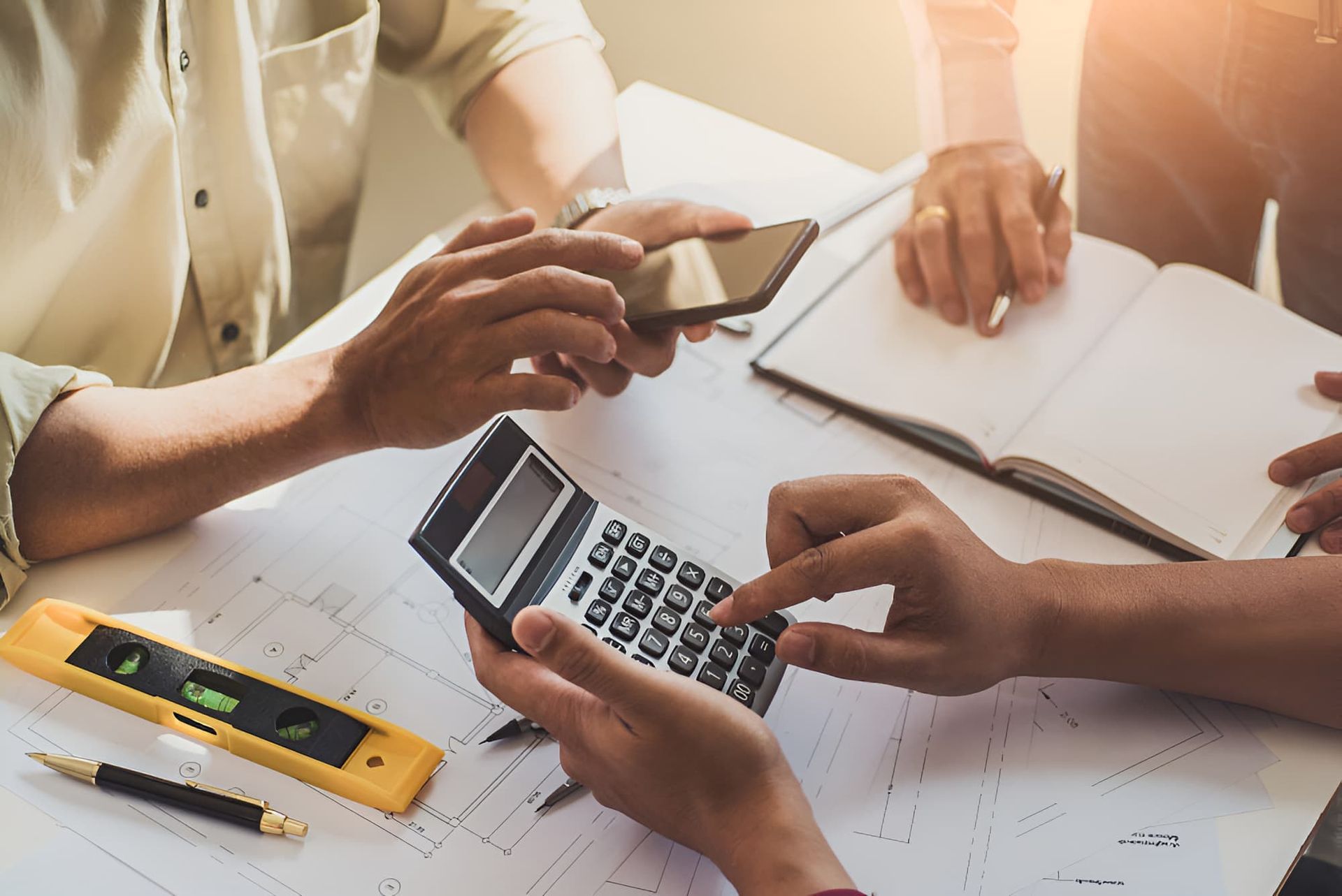 A Group Of People Are Sitting At A Table Using A Calculator — BookSenz In Cessnock, NSW