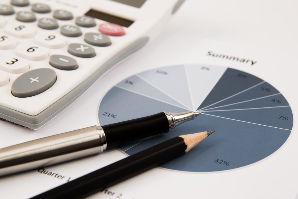 A Pen And Pencil Sit On A Pie Chart Next To A Calculator — BookSenz In Thornton, NSW