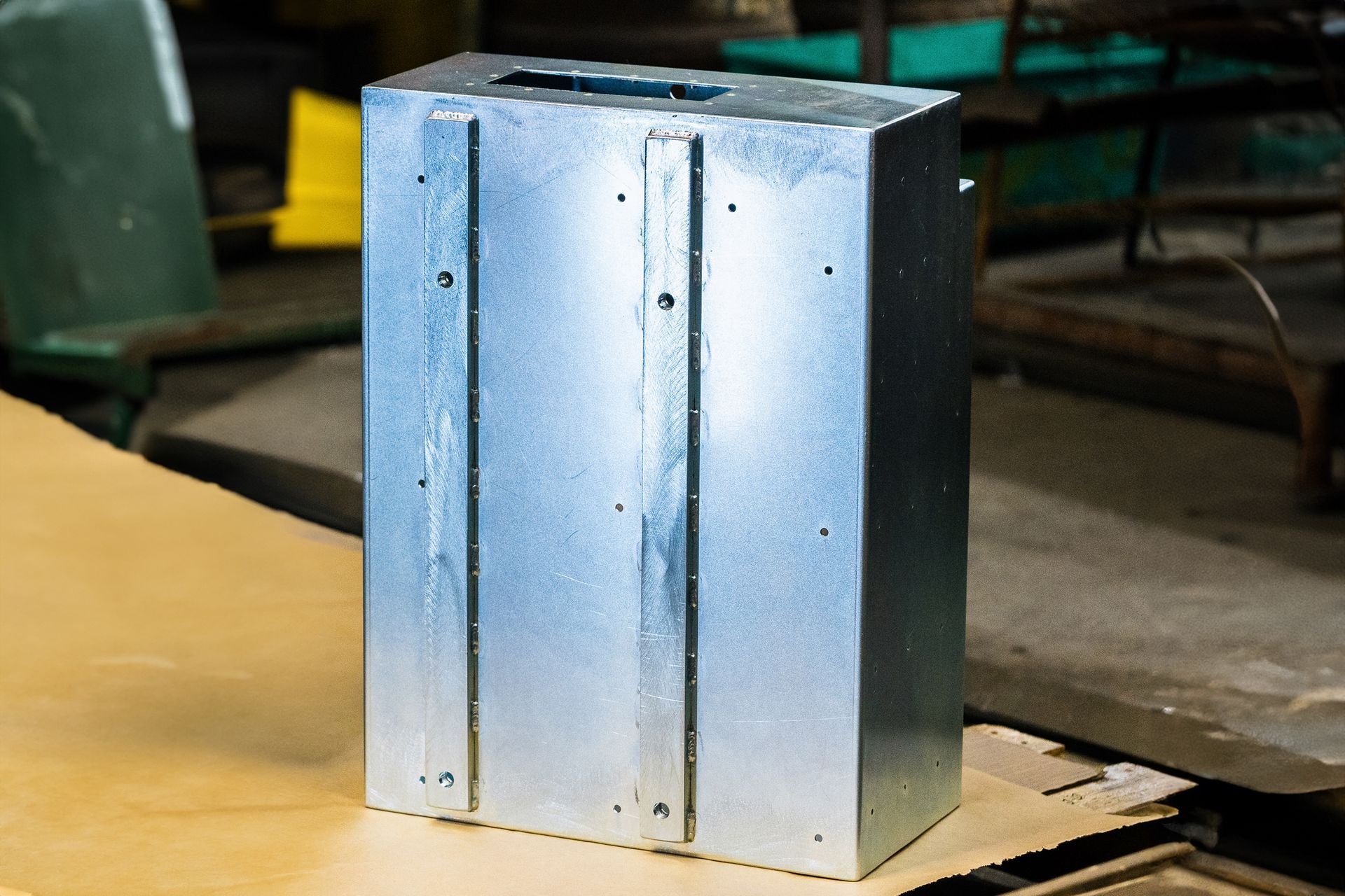 A metal box is sitting on top of a piece of cardboard.