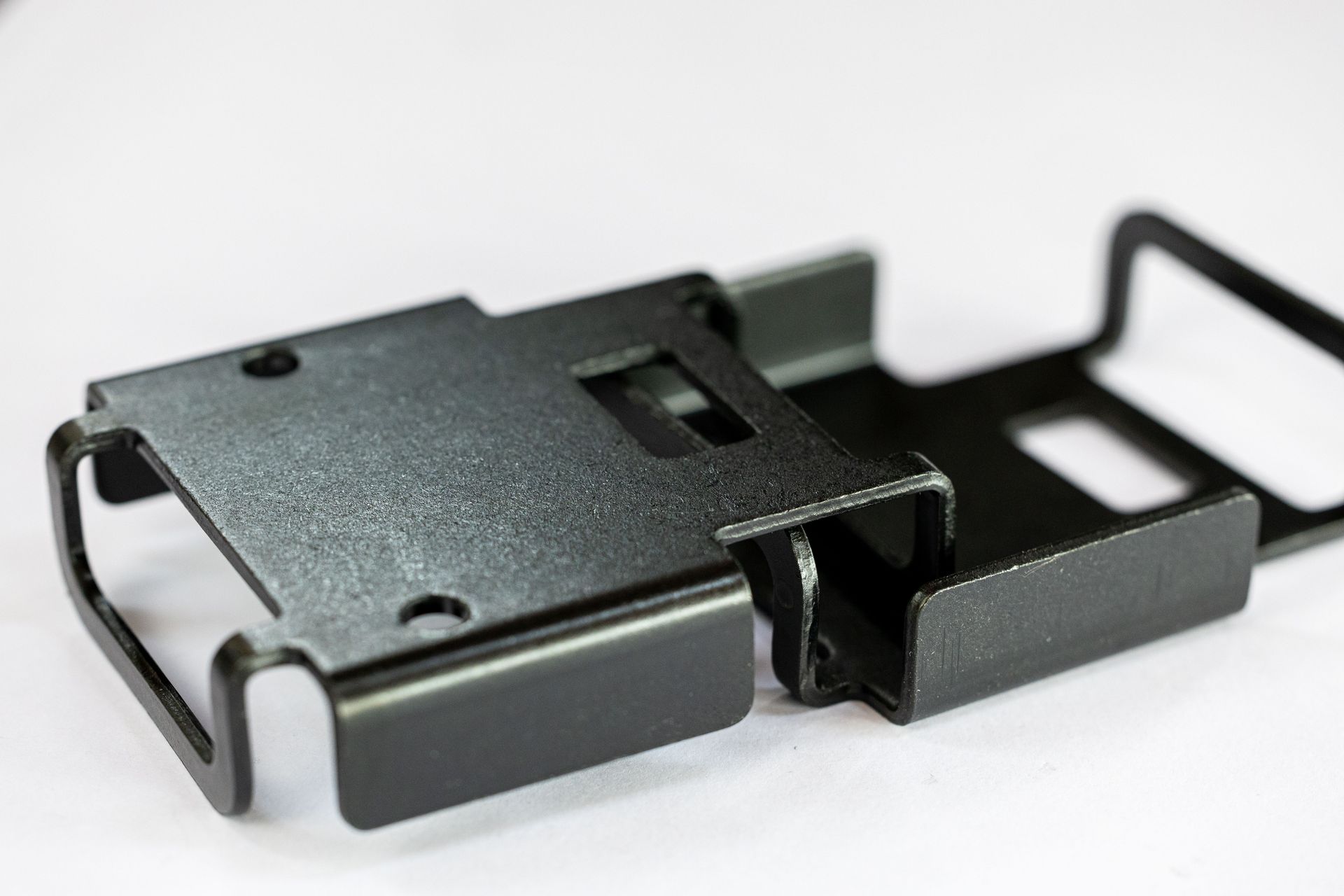 A close up of a black metal object on a white surface.