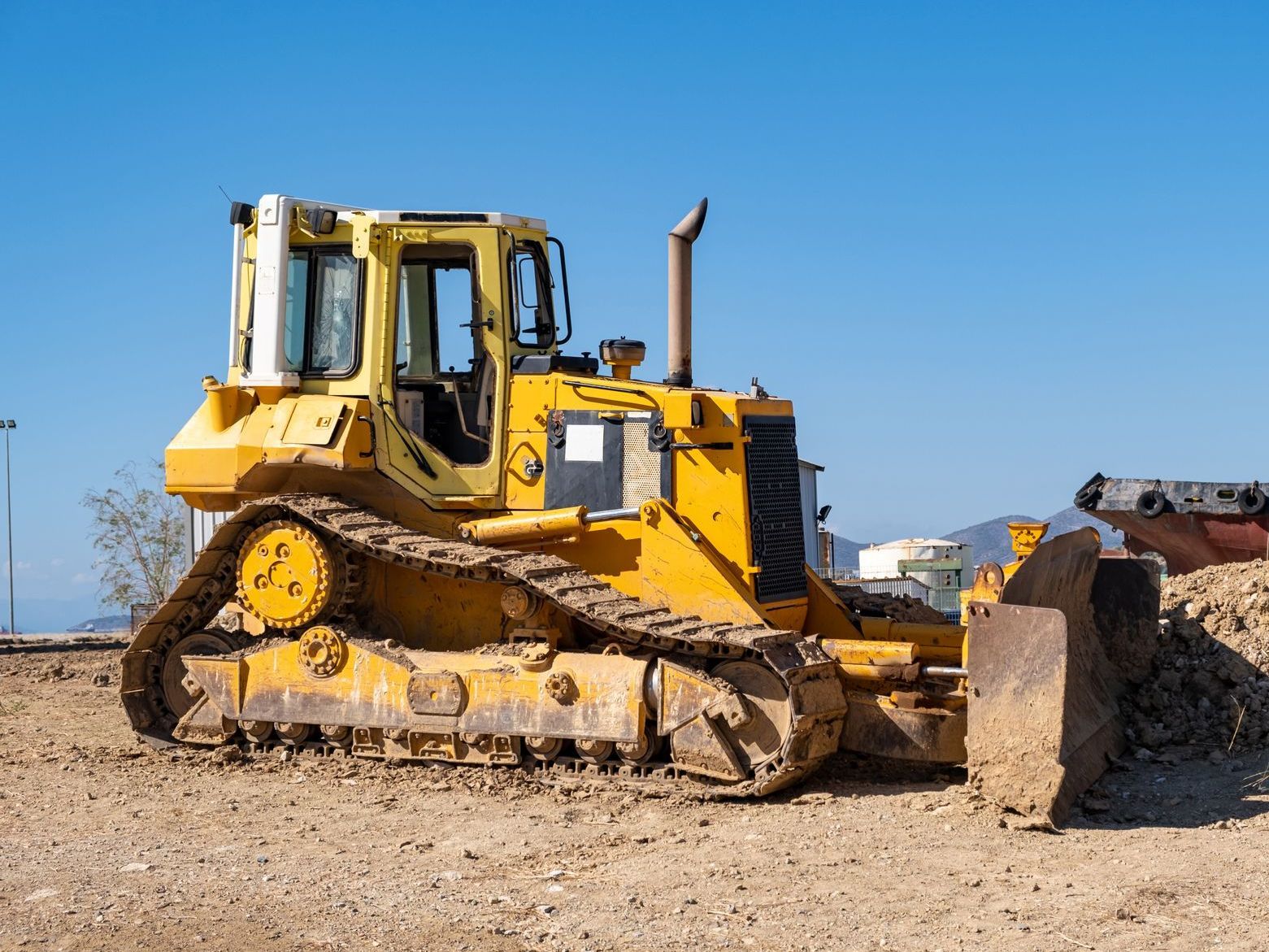 A yellow bulldozer is parked in a dirt field.