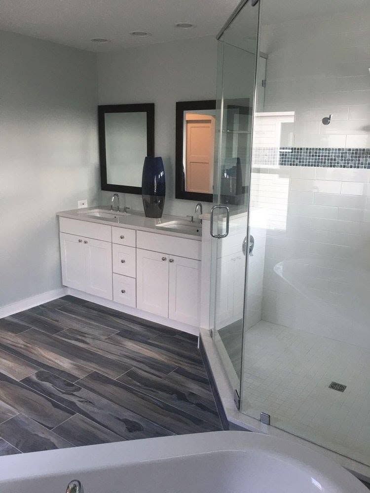 Modern bathroom with vanity, mirrors, white tile, and glass shower enclosure