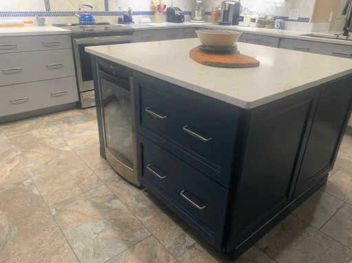 Kitchen island with dark blue cabinets and a beige countertop in a bright kitchen